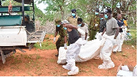 Locals help homicide detectives carry bodies of three people exhumed from a shallow grave