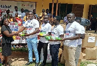 Head of Sekondi School for the Deaf receiving items from AirtelTigo's Judah Entsua-Mensah