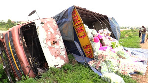 The overturned cargo truck with some of the bags of rice on the ground