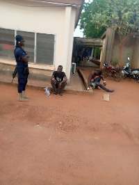 The  two suspects being guarded by an officer