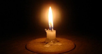 Lighted candle in darkness.    File photo.