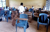 Students who sit in plastic chairs write on their laps