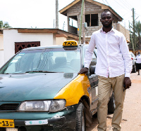 Kwasi Ackon standing beside his 'old' taxi