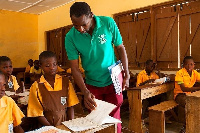 A teacher standing by a student in the classroom