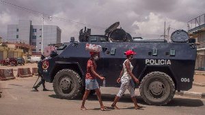 Pedestrians walk past an Angola police armoured personnel carrier seen blocking a street in Luanda