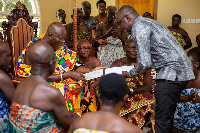 Otumfuo Osei Tutu II receiving the signed documents from Dr Kingsley Agyeman