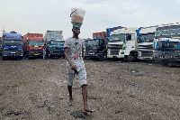 An egg-seller walks past food supply trucks parked at a garage, (Reuters)