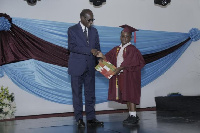 Mr Kabral Amihere presenting a prize to a graduand for topping his class in English language