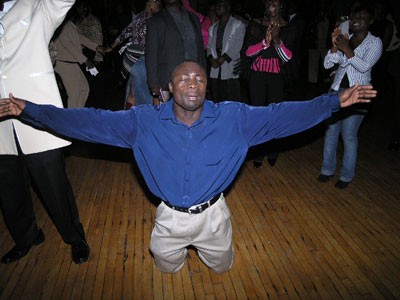 An attendee is overcome with emotions and bowed down with hands raised to praise his almight