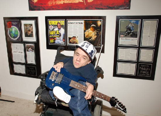 Simon posing with his customize guitar.  Behind is the Urban hits
magazine feature which also included Jay Z