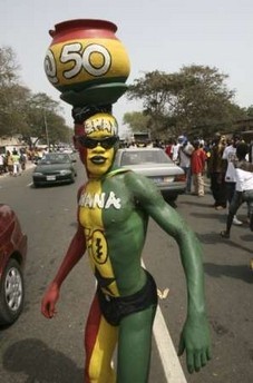 A man painted in the colours of Ghana's national flag stands on a street